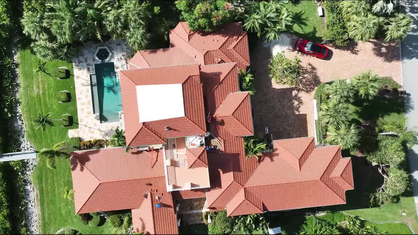 Overhead aerial view of a large tile-roofed home with a pool and garden