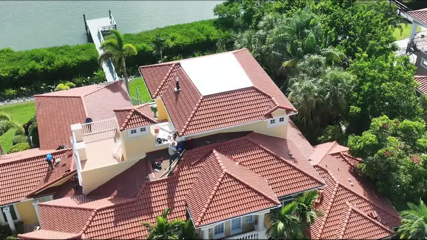 Aerial view of roofers on a tile roof at a home backing onto open water